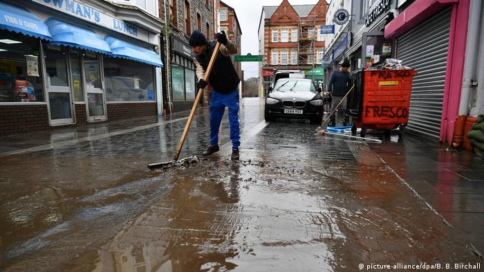 Man sweeps flood waters in streets