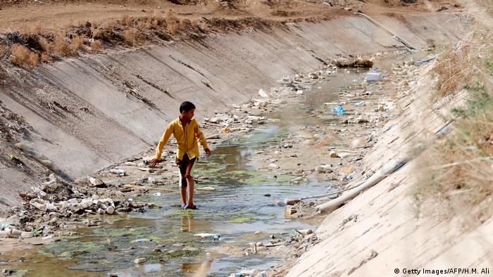 A boy walks through a dried up dyke in Iraq