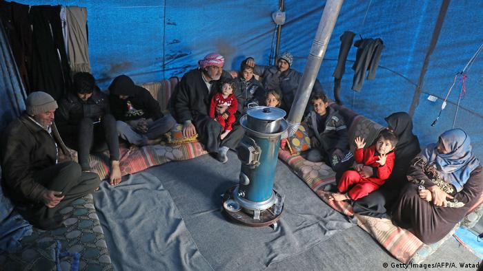 Syrian Abdel Razzak Sallat sit with his family inside a tent at an informal camp for the displaced in Kafr Lusin village
