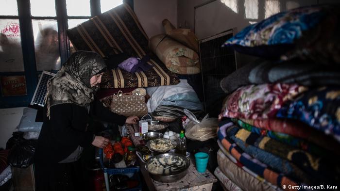 Displaced Syrian woman cooks in a classroom of a primary school turned into a makeshift refugee shelter