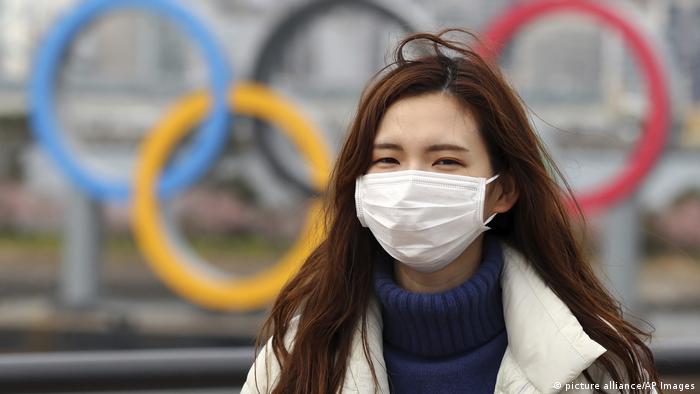 A woman wearing a mask walks near the Olympics' mark in Odaiba, Tokyo (picture alliance/AP Images)
