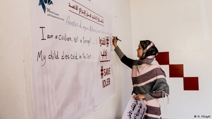 Huda Khayti writes on a sheet on the wall in Idlib (H. Khayti)
