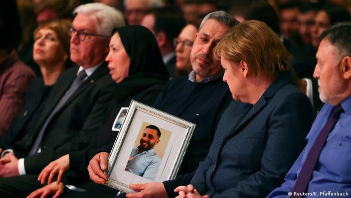 Germany's Chancellor Angela Merkel looks at the picture of a victim of the shootings in Hanau as she attends the memorial service for the victims of the shootings in Hanau, Germany, March 4, 2020. (Reuters/K. Pfaffenbach)