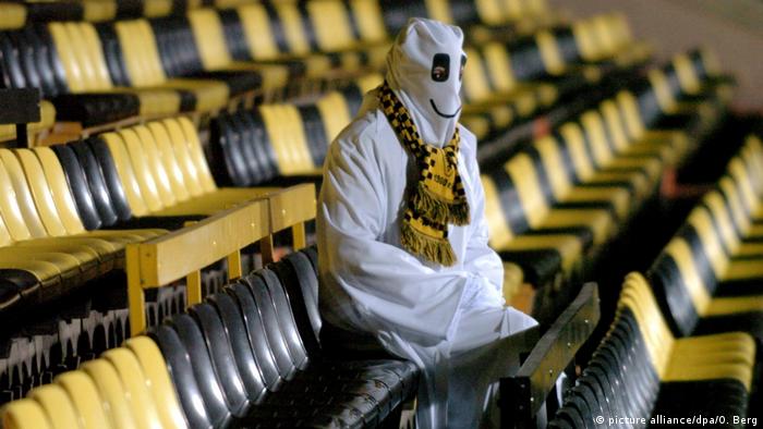 A fan dressed as a ghost sits alone in a stadium