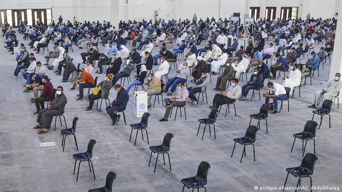 A hall for testing is lined with hundreds of well spaced apart seats. Hundreds in masks sit and wait. 