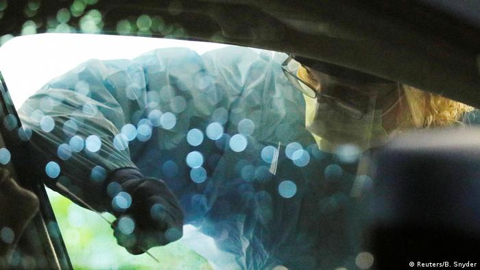Medical personnel swab a driver's nose at a drive-through coronavirus testing site in Seattle, Washington