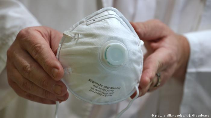 A pharmacist holds up an FFP2 mask