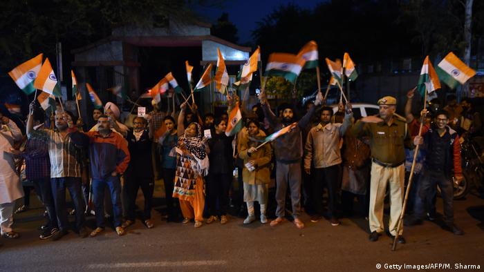 Indianos reunidos do lado de fora da prisão na sexta-feira (20/03). Eles empunham bandeiras indianas e comemoram execução dos condenados por estupro coletivo em ônibus ocorrido em 2012.