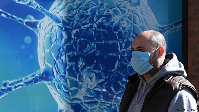 Мужчина в маске на фоне символического изображения вируса
