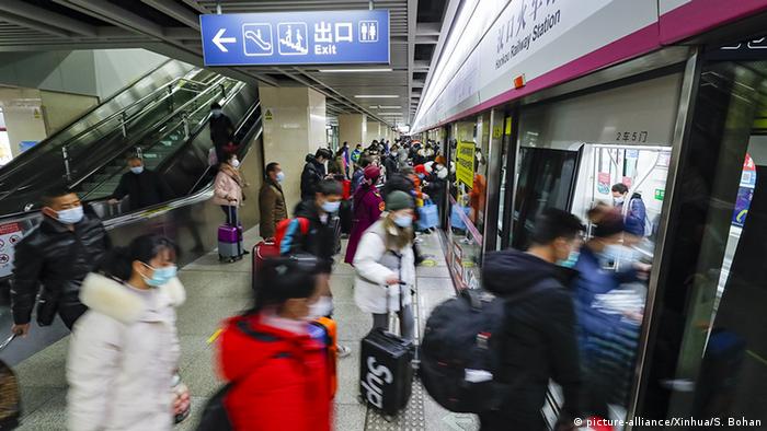 Pessoas usando máscaras entram no metrô em Wuhan
