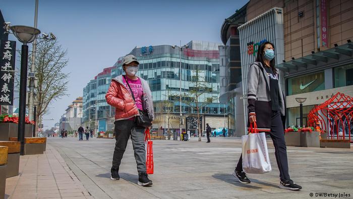 Women wearing masks for protection against COVID-19 walk on Wangfujing shopping street in Beijing, China