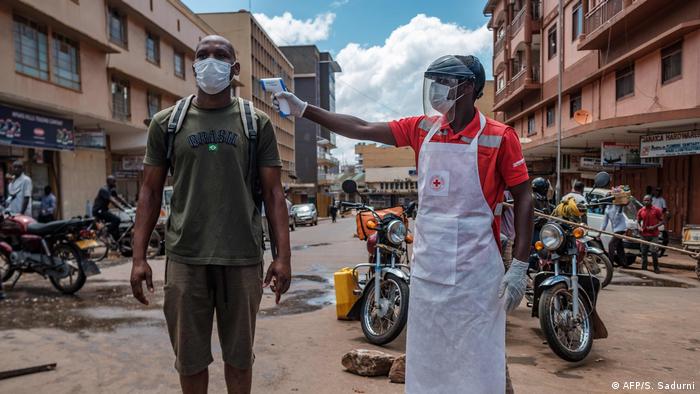 A Red Cross volunteer measures temperature of a man in Kampala. (AFP/S. Sadurni)
