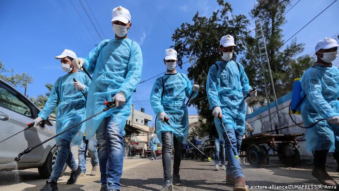 Palestinian workers spray disinfectant as a preventive measure amid fears of the spread of the coronavirus disease