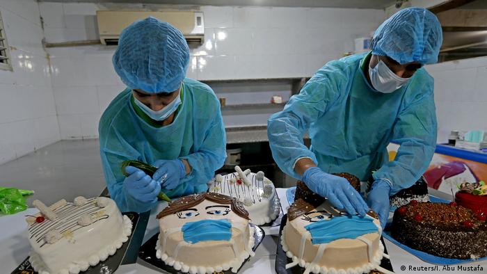 Palestinians put final touches on cakes shaped like a character wearing a mask
