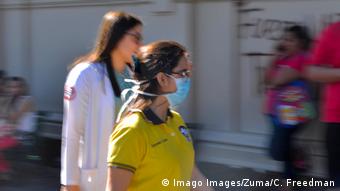 Foto de mujer con mascarilla caminando en una calle salvadoreña