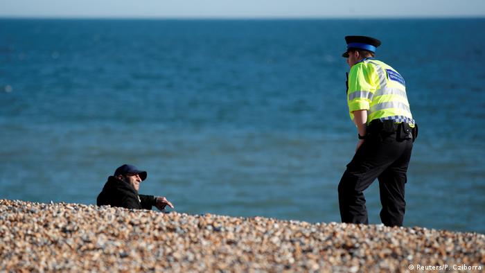 A police officer and a person on a beach in Brighton, England (Reuters/P. Cziborra)