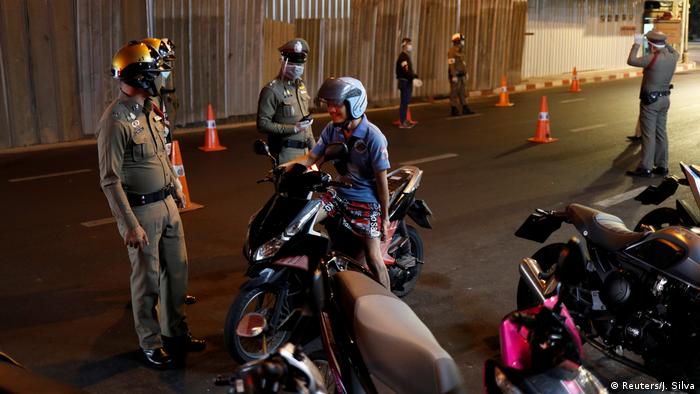 Thai police officers wearing protective masks stop a motorcycle driver (Reuters/J. Silva)