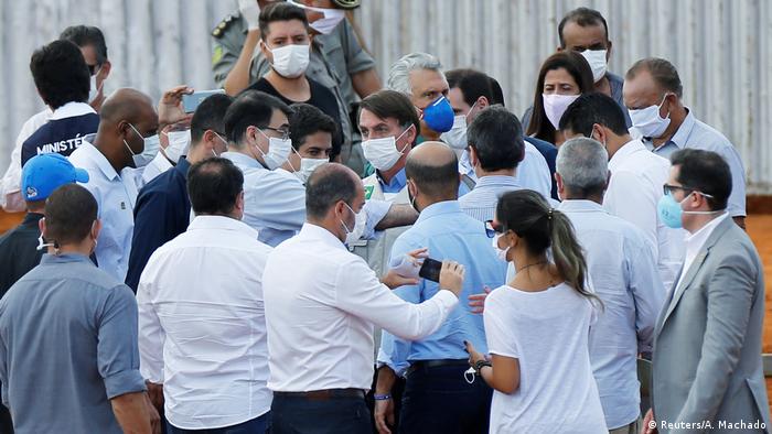 Bolsonaro, de máscara, é rodeado pormuitas pessoas também usando máscaras. 