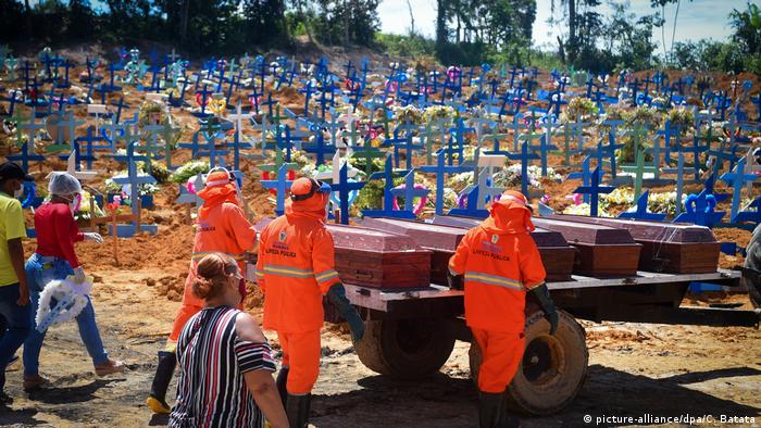 Brazilian authorities in protective gear bring coffins to a mass gravesite (picture-alliance/dpa/C. Batata)