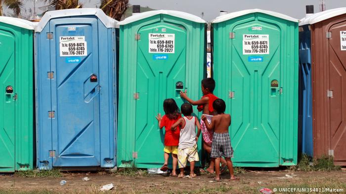 Four little boys crowd around a porta potty in the Philippines (UNICEF/UNI154811/Jeoffrey Maitem)