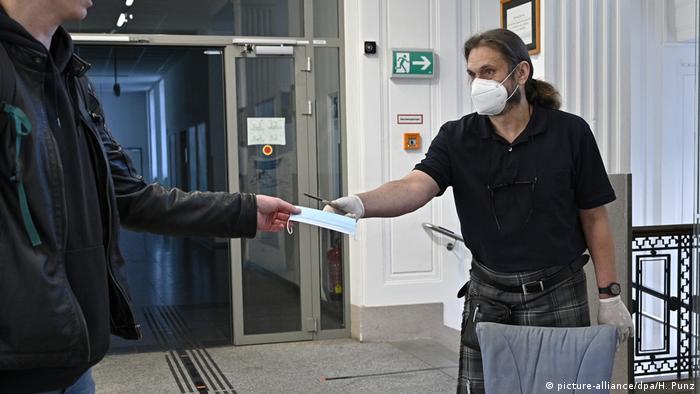 A teacher hands a face mask to a pupil before lessons begin at a high school in Vienna, Austria. 