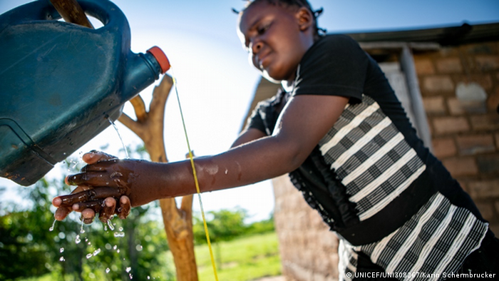 A girl washes her hands beneath a faucet made from an old plastic container (UNICEF/UNI308267/Karin Schermbrucker)