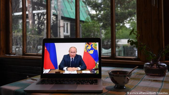 На столе стоит компьютер, по которому смотрят выступление Путина