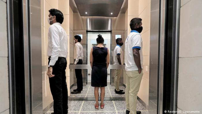 People practice social distancing inside an elevator prior to arriving to their work places at World Trade Center, after the government announced that private and state companies will reopen their offices
