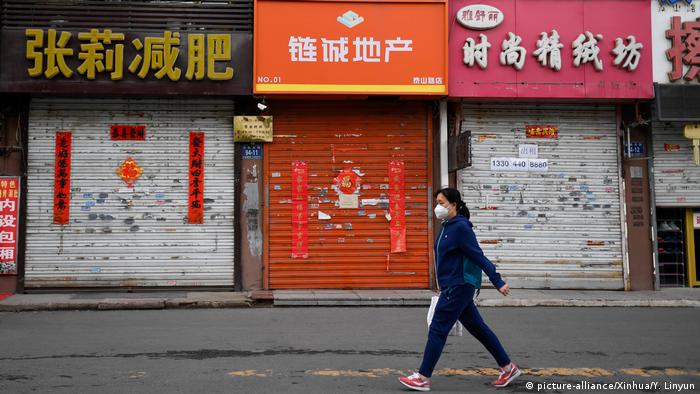 A woman walks past closed stores in Fengman District of Jilin City (picture-alliance/Xinhua/Y. Linyun)