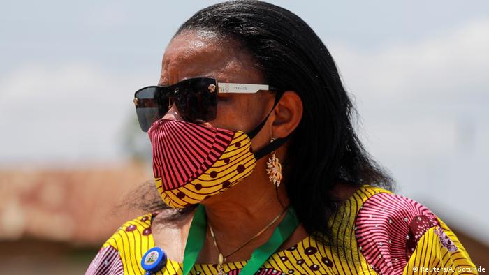 A woman wears a mask made from the same fabric as her dress