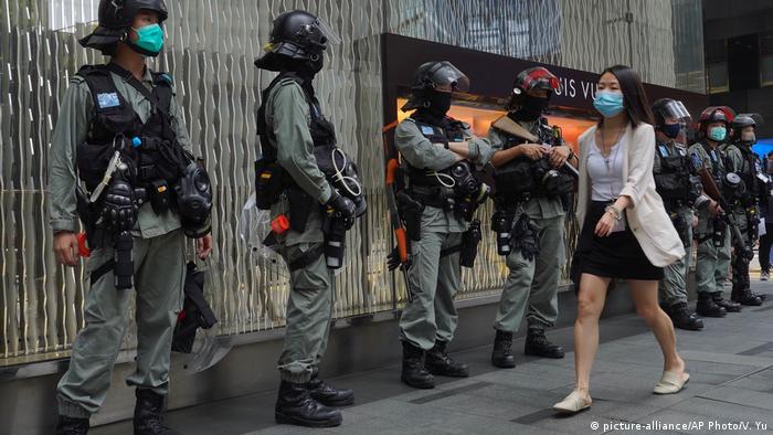 A woman walking past a row of police in riot gear (picture-alliance/AP Photo/V. Yu)
