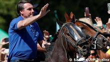 Jair Bolsonaro acena sobre um cavalo