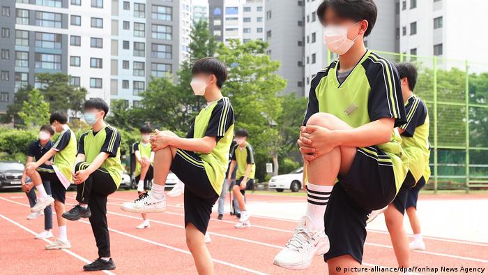 A physical education class in progress with students wearing masks at a high school in Gwacheon, South Korea. In addition to regular sanitizing and multiple temperature checks between classes, students are required to keep their masks on at all times, except when they are eating. 