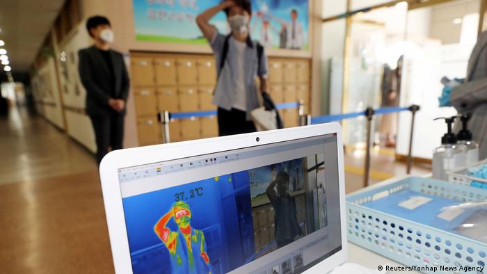 Students wait in line as staff conduct temperature checks with a thermal imaging camera in Chungju, South Korea. The latest phase of reopening has brought nearly 1.8 million children back to school. 
