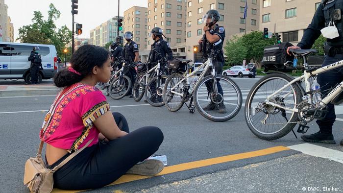 A young woman sits on the street in front of a row of police (DW/C. Bleiker.)