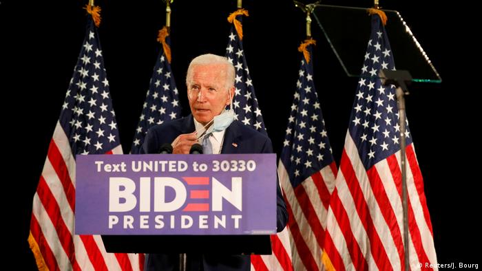 Joe Biden pulls away his coronavirus face mask as he speaks at a rally in Delaware (Reuters/J. Bourg)