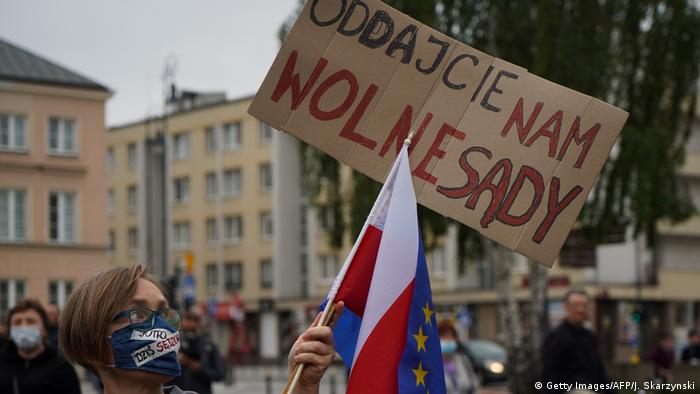 A protester wearing a mask waves a Polish flag outside the Supreme Court in Warsaw