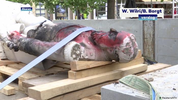 A damaged statue of former Belgian King Leopold II is seen being removed