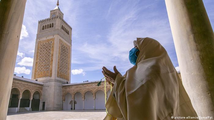 Жительница Туниса в защитной маске на фоне мечети