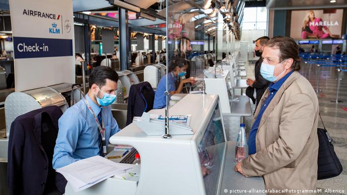 On the first day of the reopening of Malpensa Airport, a man checks in for his flight wearing a mask