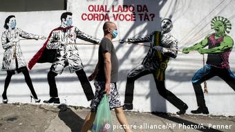 Мужчина в маске и граффити в Сан-Паулу о борьбе врачей с вирусом SARS-CoV-2