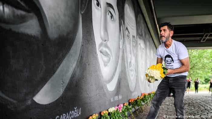 Brother of one of the victims lays down flowers at mural (picture-alliance/dpa/A. Arnold)