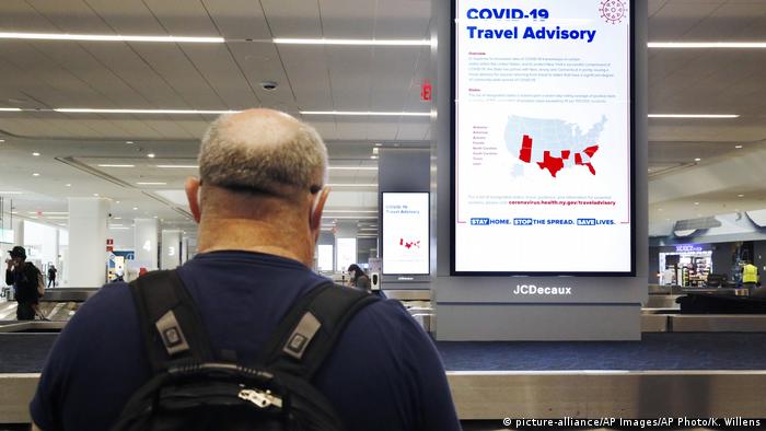A traveler at New York's LaGuardia airport reads a COVID-19 travel advisory sign (picture-alliance/AP Images/AP Photo/K. Willens)