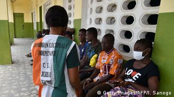 Un responsable de la Commission électorale s'occupe de personnes devant le centre d'inscription des électeurs le 4 juillet 2020, à Abidjan, à la veille de la clôture des inscriptions sur la liste électorale de la présidentielle du 31 octobre.