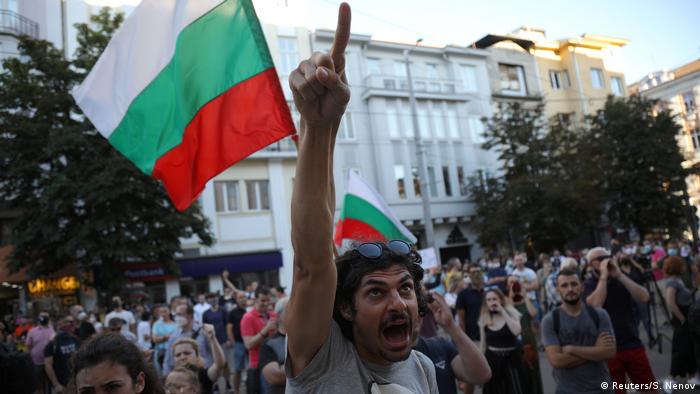 A man shouts and points his finger in front of a Bulgarian flag during demonstrations