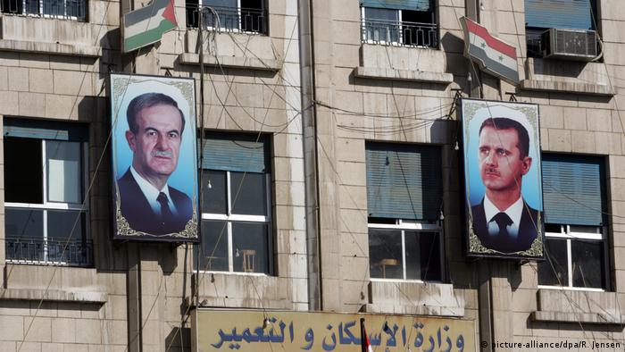 Портреты отца и сына Асадов, висящие на фасаде здания