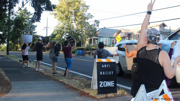 Protesters hold anti-racism signs and hold their hand up during in a demonstration on a residential street