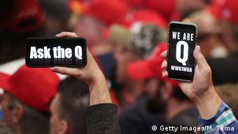 Two men are holding mobile phones, on the screens of which it is written in English: Ask Q and We Q