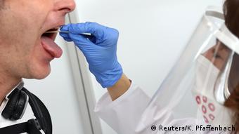 Сотрудник аэропорта делает мужчине тест на коронавирус