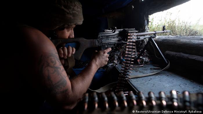 A Ukrainian soldier aims a machine gun out of a pillbox